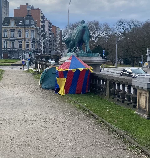 A circus like tent pitched next to a regular 2 second tent in a park.