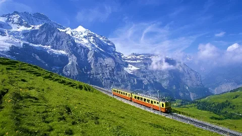 A red and yellow old style train in the middle of the Swiss alps.