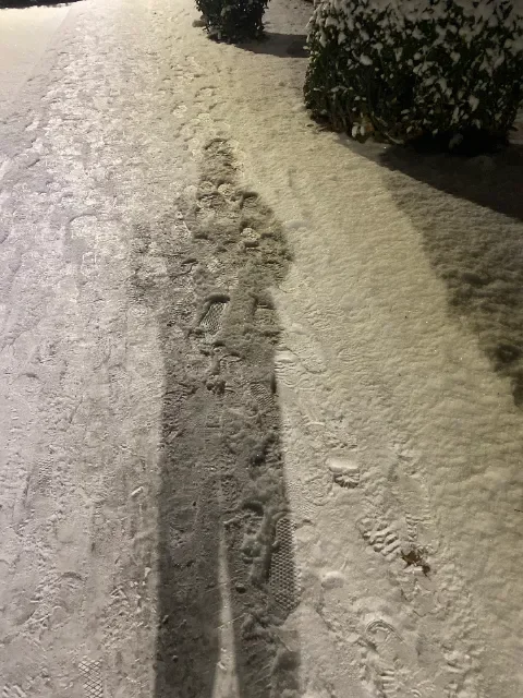 My shadow at night on a snow covered sidewalk.
